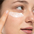 Close-up of a woman applying under eye cream to her face